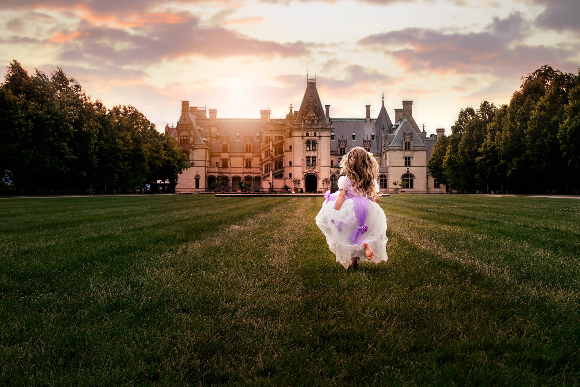a little girl in a princess dress running toward the Biltmore House at sunset which is part of the fun things to do in asheville with kids list