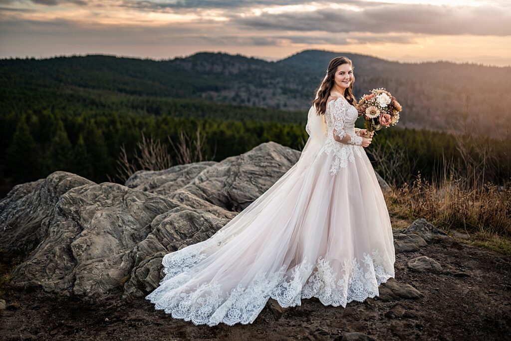 A beautiful bride with her
 flowers with mountains in the distance at sunset. 