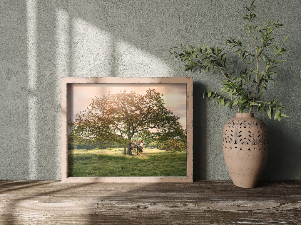 a framed heirloom print of a family sitting on a large tree at sunset.