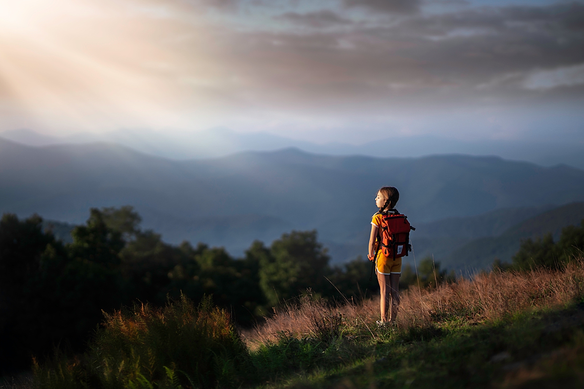a young girl with a red backpack taking in the view while hiking on Bear Wallow Mountain