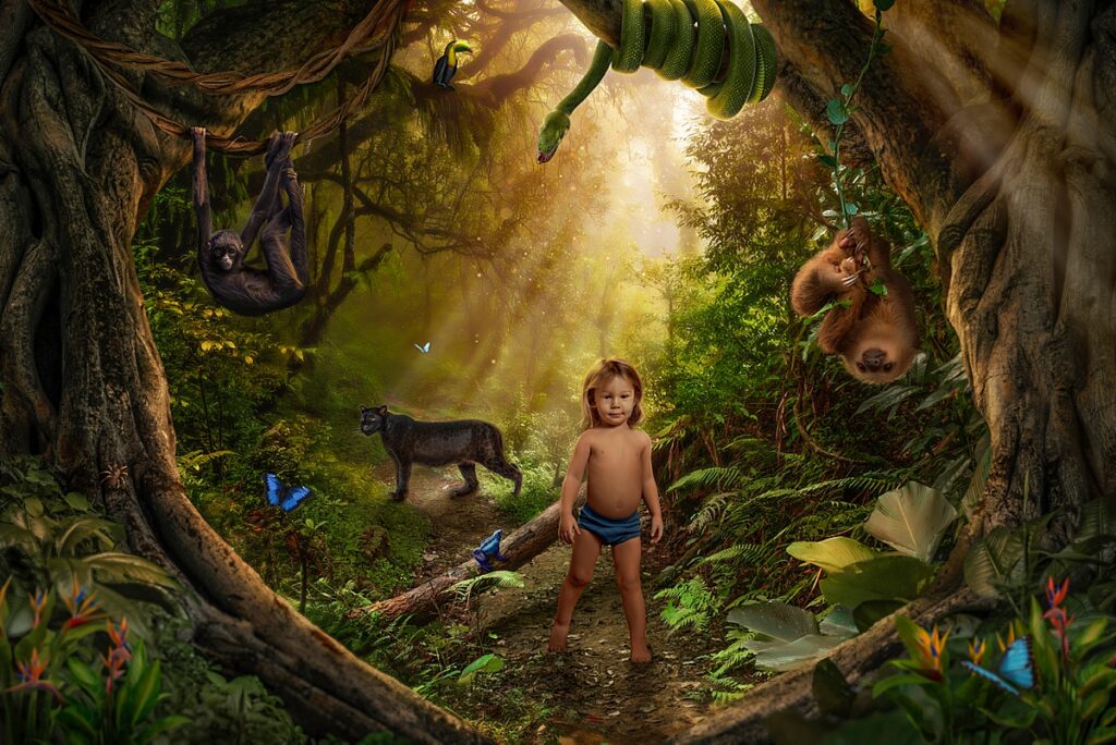 A little boy in blue shorts stands in a sunlight jungle with his jungle animal friends all around. 