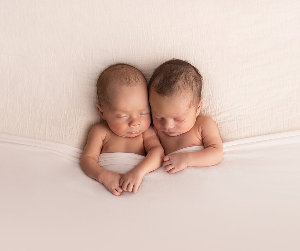 newborn baby boy twins snuggling under a blanket during their newborn session with the best newborn photographer in Asheville