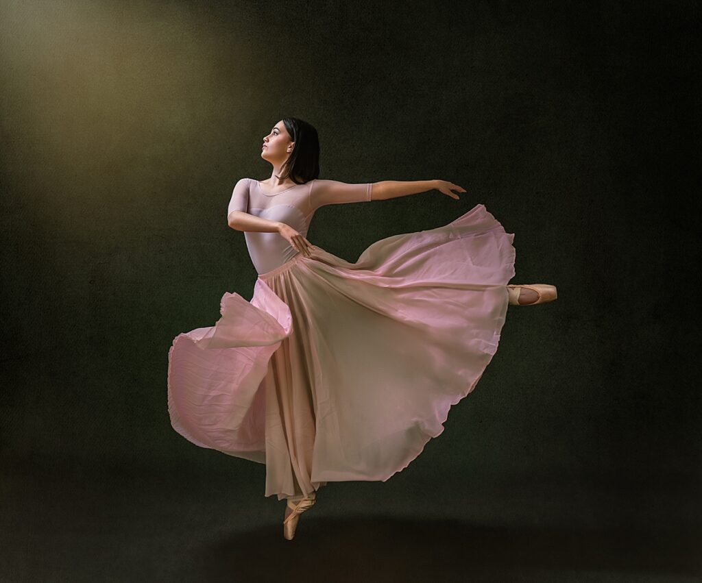 A beautiful ballerina dances on pointe in a long flowy pink dress