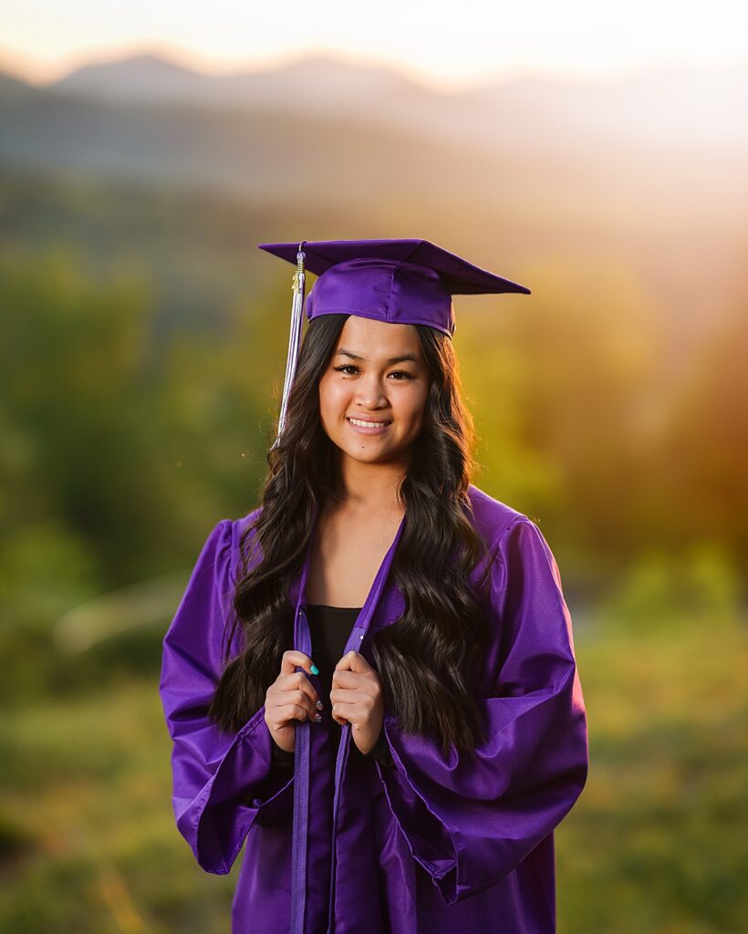A high school graduate in her purple cap and gown smiles during her Asheville Senior Photo Session 