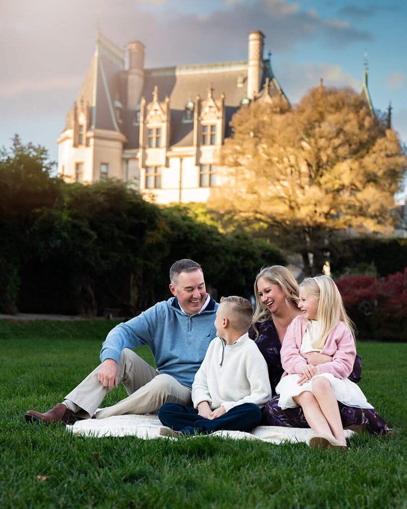 A family snuggles and laughs with the sun setting on the Biltmore Estate behind them during their session with a Biltmore Estate Photographer. 