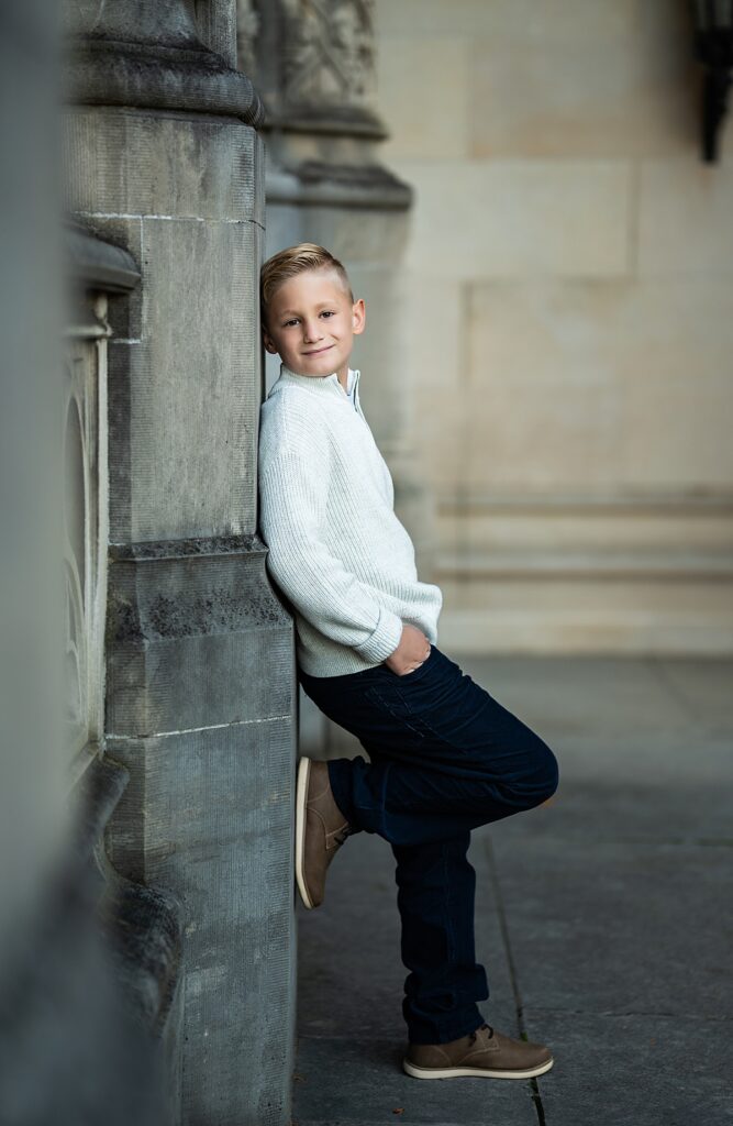 a young boy leans on a pllar in front of the Biltmore Estate in Asheville, NC